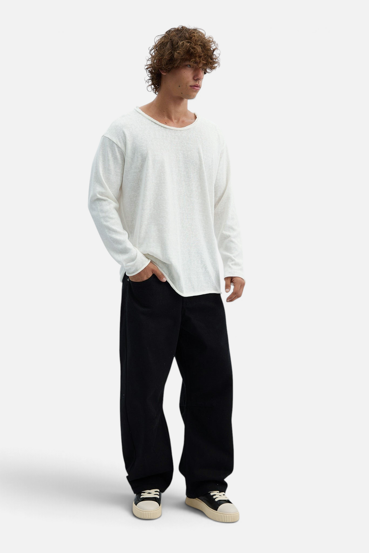 Mainstreamonline black loose-fit drill pants worn by a man with curly hair paired with a white long-sleeve shirt
