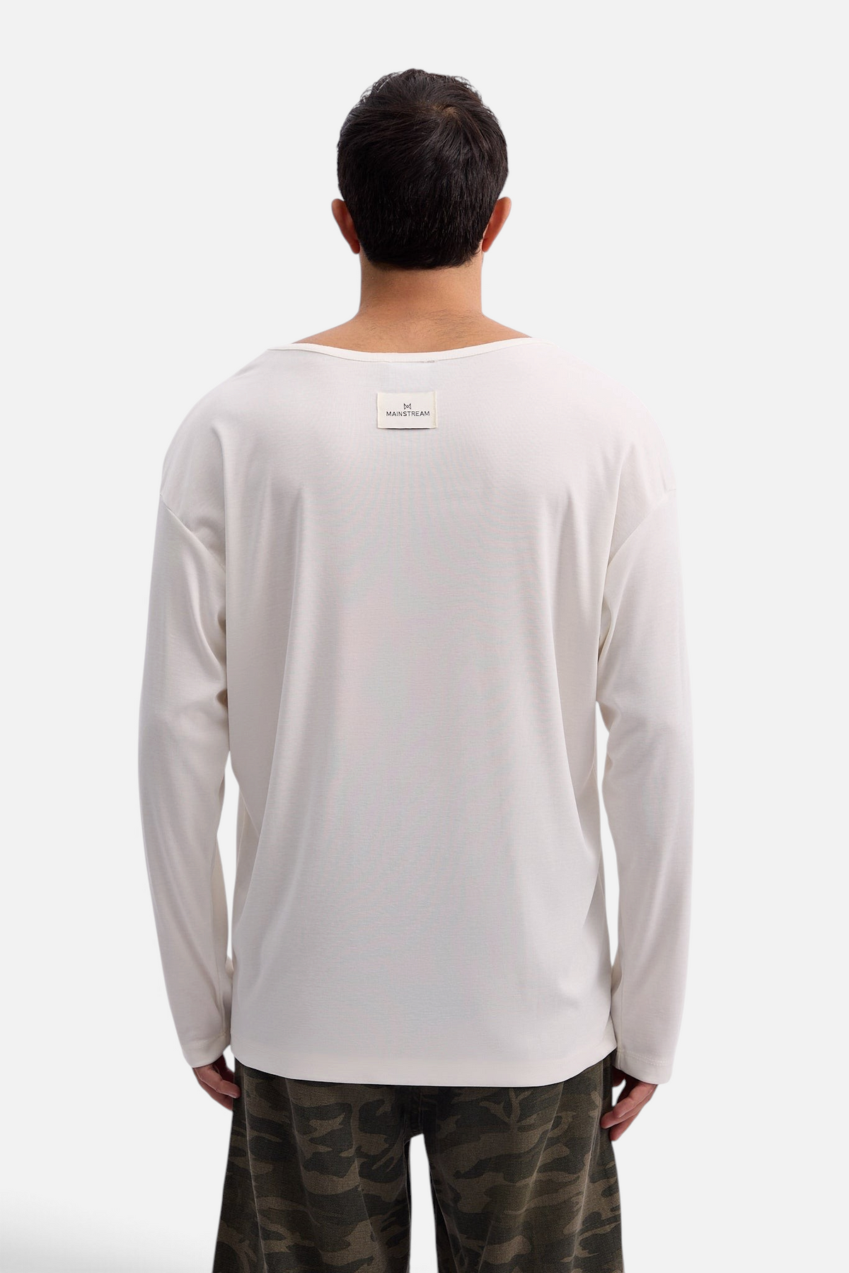 Mainstreamonline Niki long sleeve oversized off-white t-shirt with back logo patch worn by a man