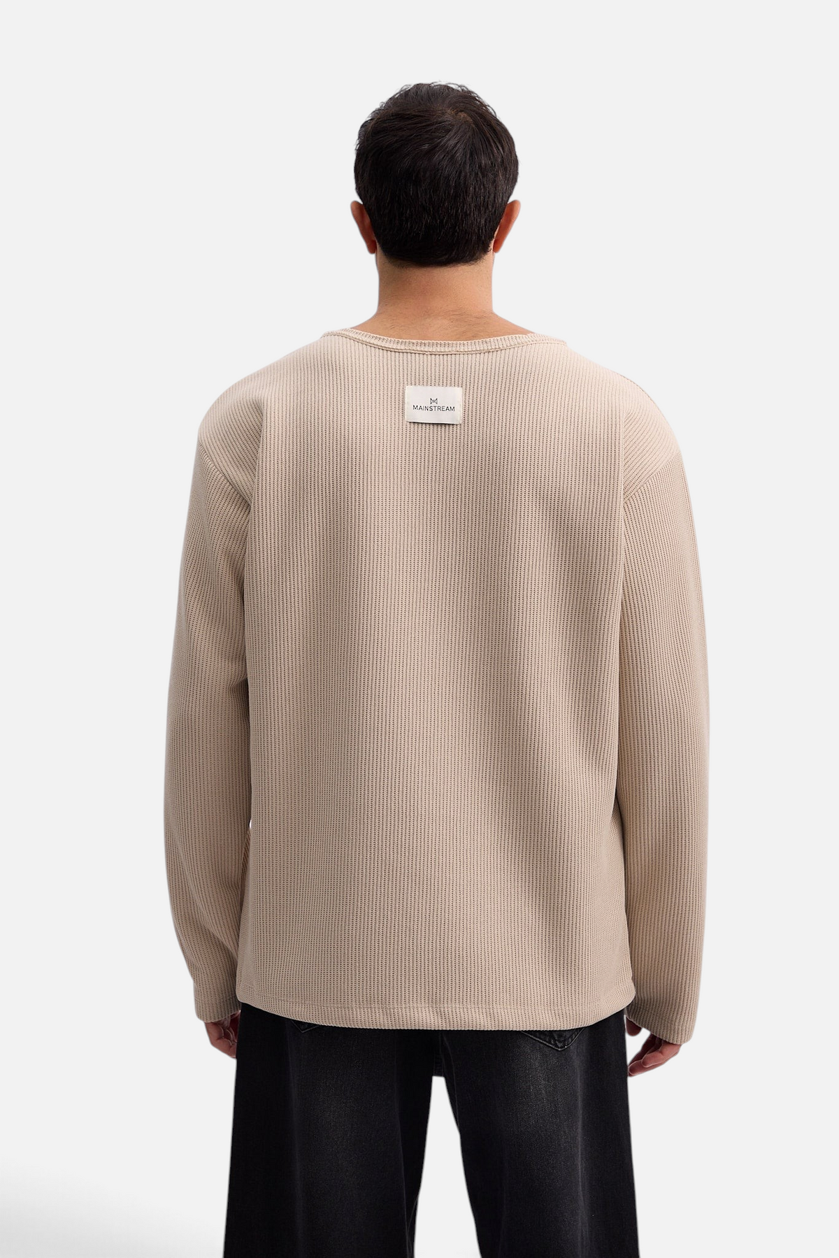 Back view of a man wearing a beige Mainstreamonline Sean Knit oversized waffle-texture sweater with a logo patch.