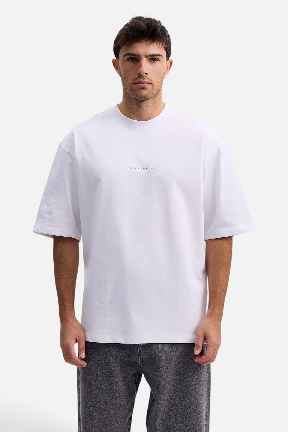 Mainstreamonline white oversized t-shirt with small chest print worn by a male model on a white background