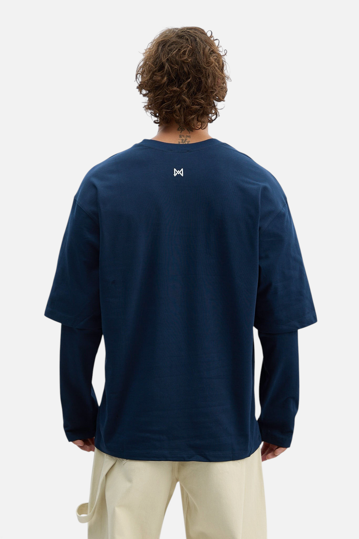 Mainstreamonline navy blue long sleeve oversized t-shirt with small white logo on back, worn by a man