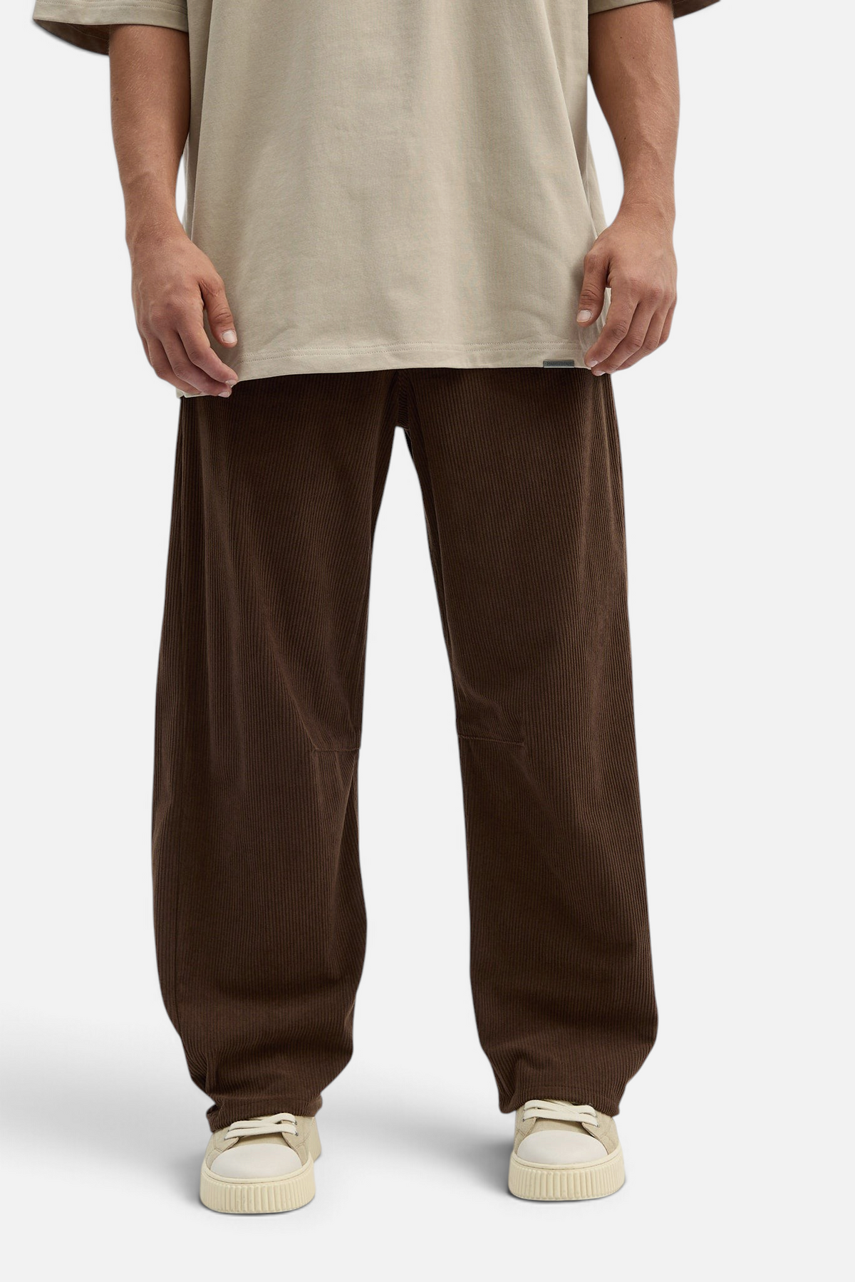 Mainstreamonline brown corduroy baggy pants with a loose, relaxed fit worn with a beige t-shirt and sneakers