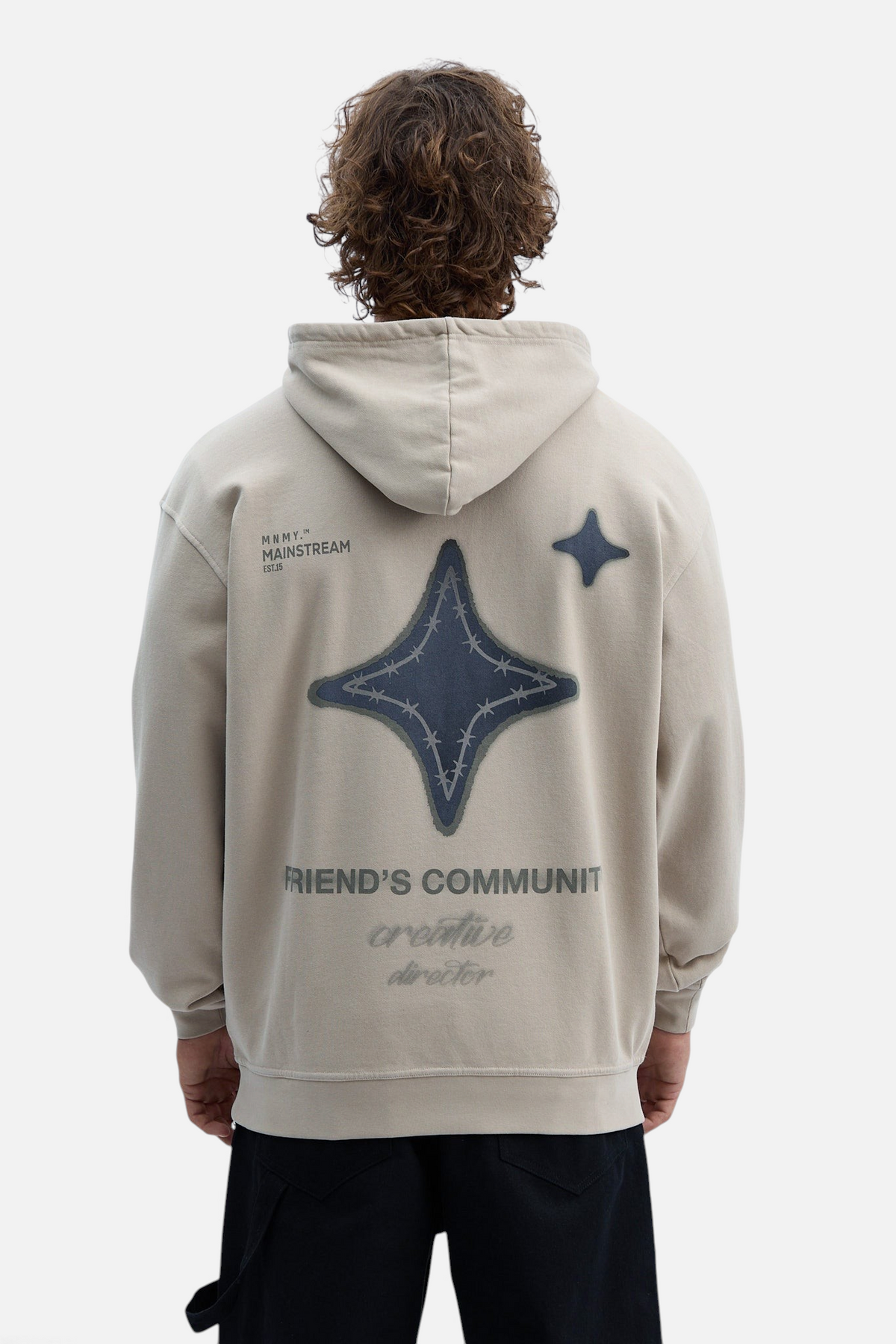 Mainstreamonline oversized beige hoodie with a large dark star graphic and text on the back, worn by a man.