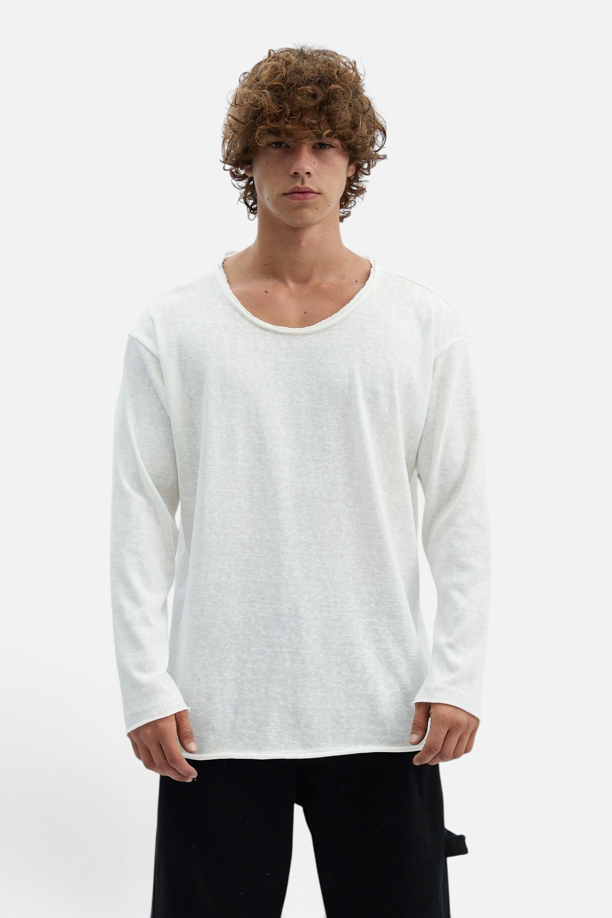 Mainstreamonline white long sleeve oversize t-shirt with a raw edge neckline worn by a man with curly hair