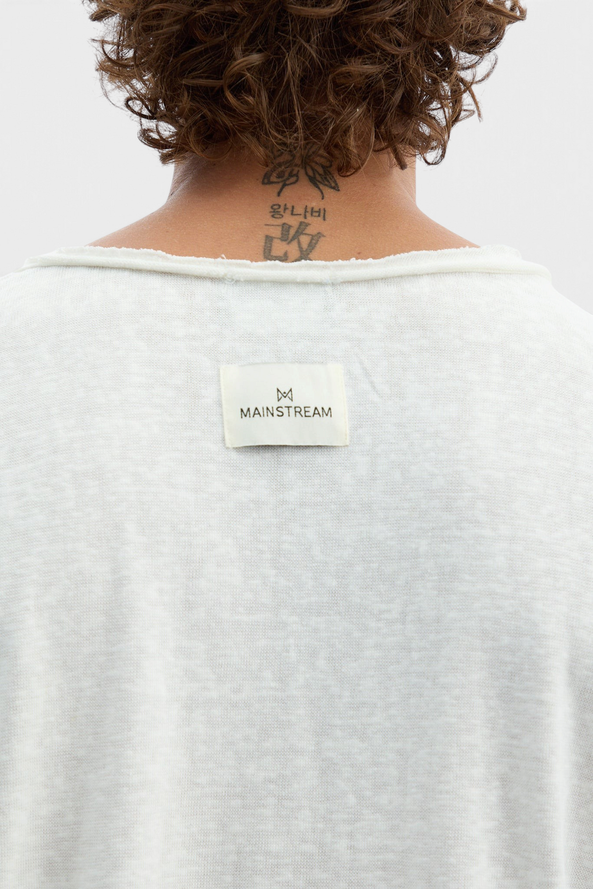 Mainstreamonline white long sleeve oversized t-shirt with raw edge neckline and branded label on the back