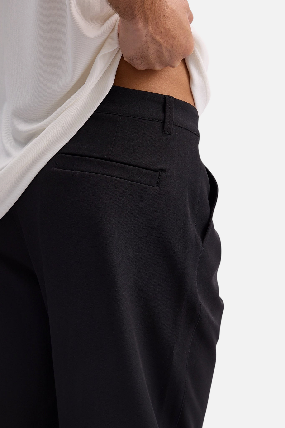 Mainstreamonline Santo Pants in black, featuring a relaxed wide-leg tailored fit and side pockets on a male model.