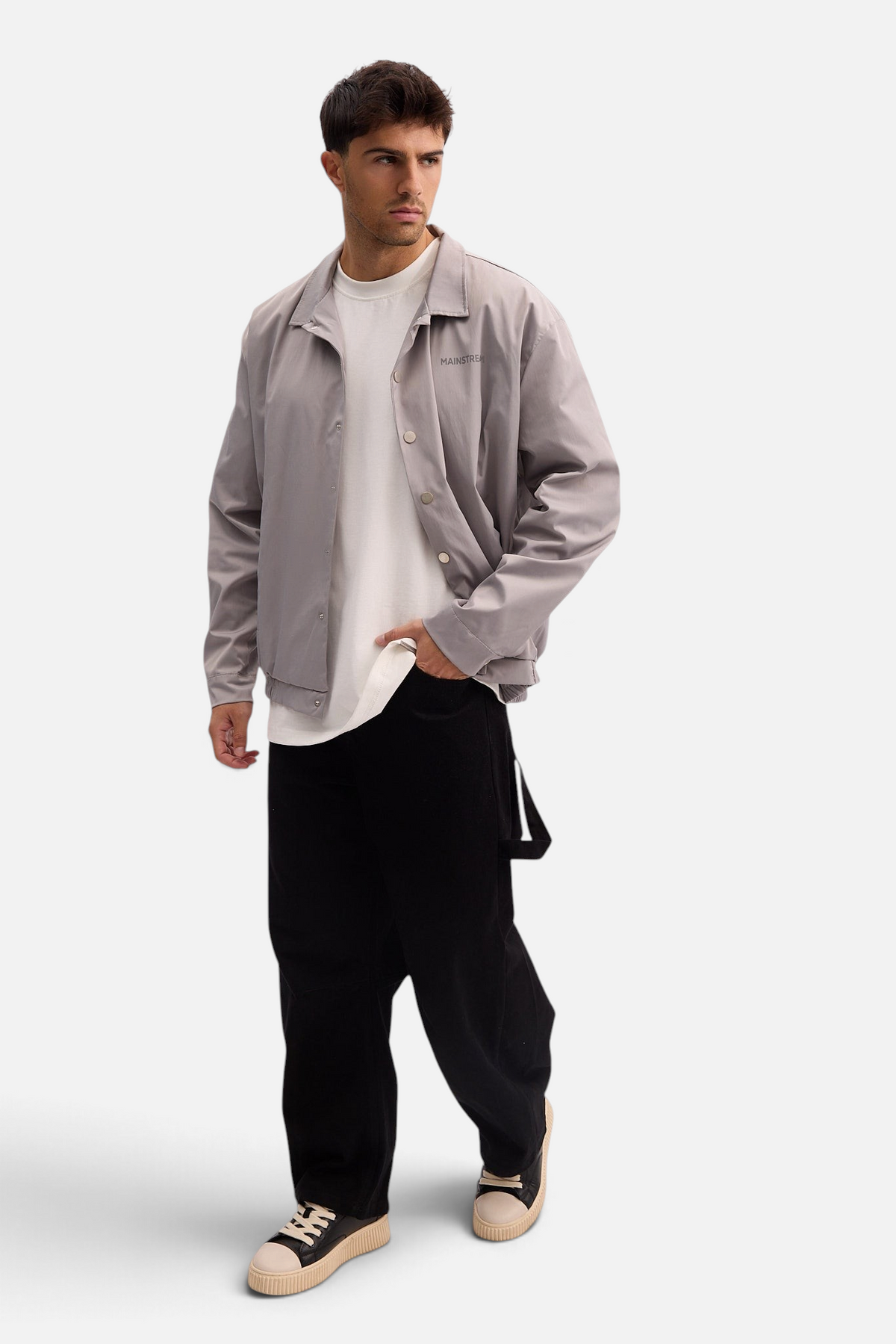 Mainstreamonline grey nylon jacket with a classic straight fit, worn by a model over a white t-shirt and black pants.
