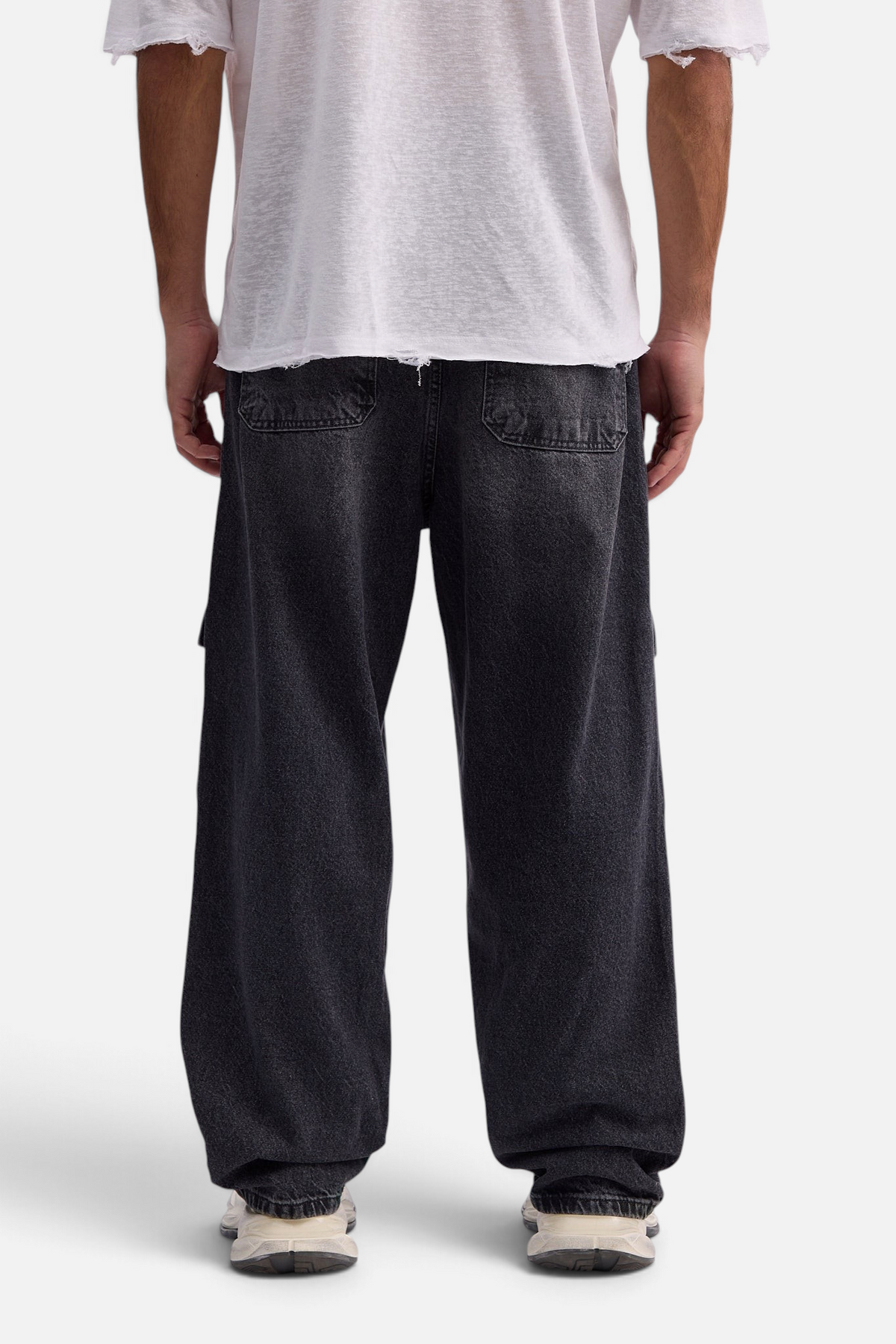 Mainstreamonline baggy skater jeans in washed black denim with a loose, relaxed fit worn by a man from behind