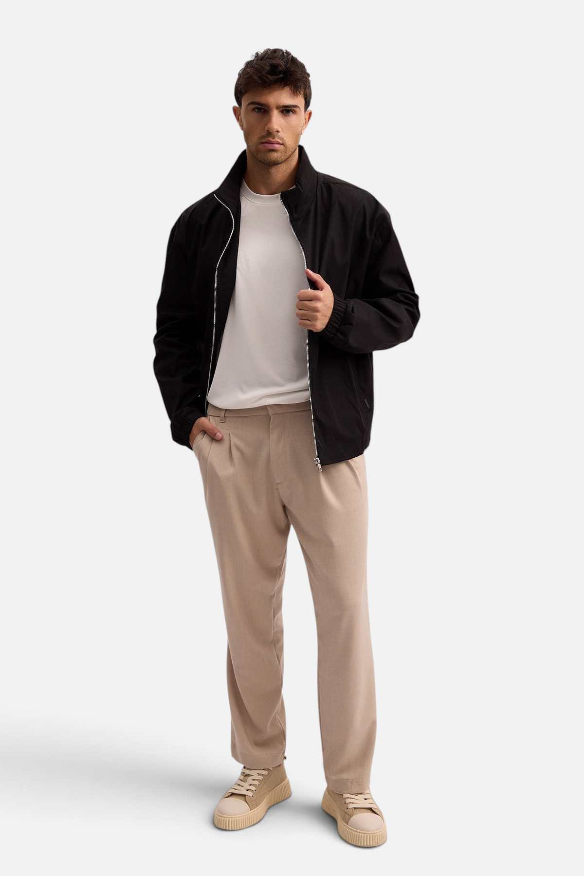 Mainstreamonline Max Pants in beige with a loose, relaxed fit worn by a model with a black jacket and white shirt