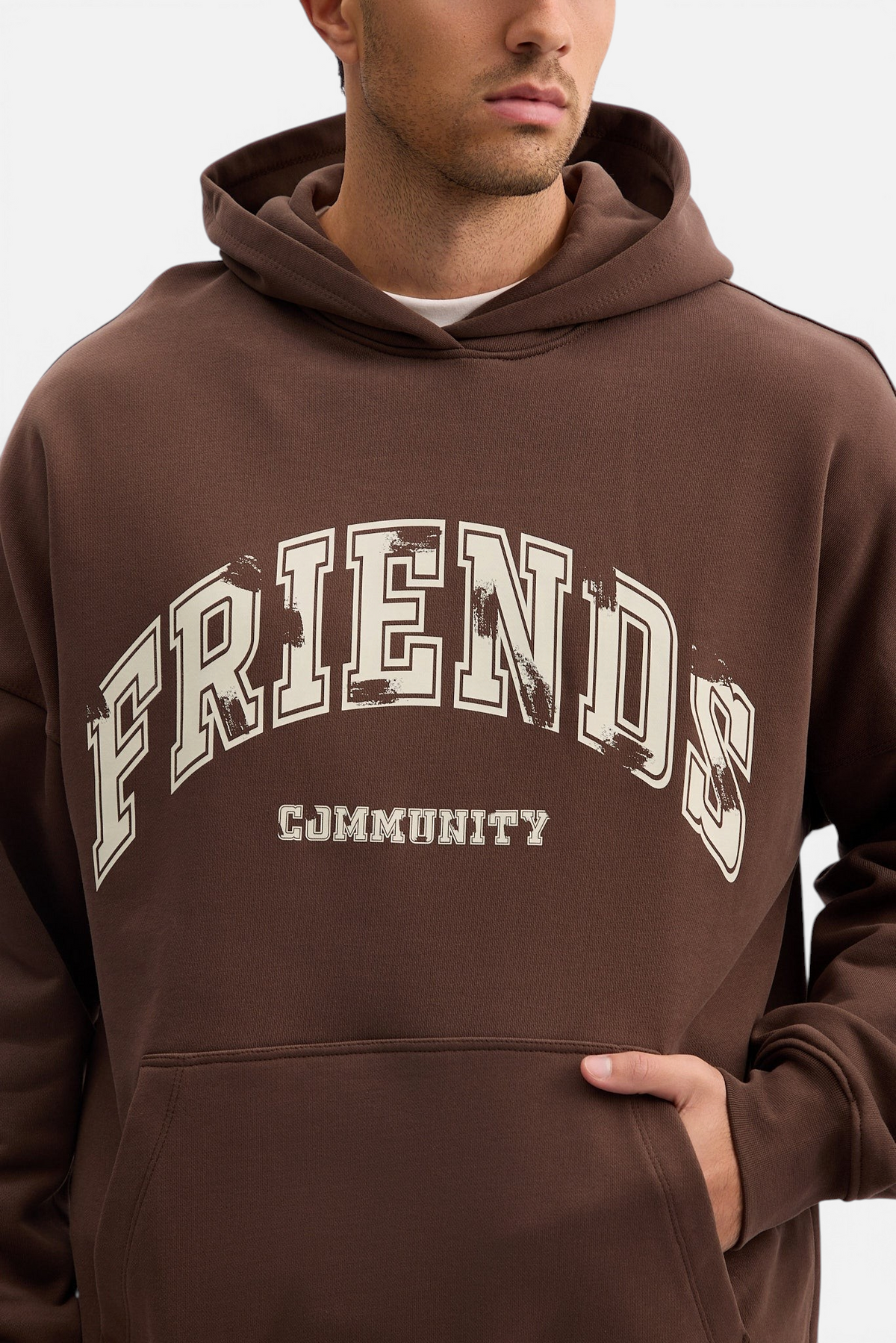 Mainstreamonline brown oversized hoodie with Friends Community graphic print and front kangaroo pocket on a model