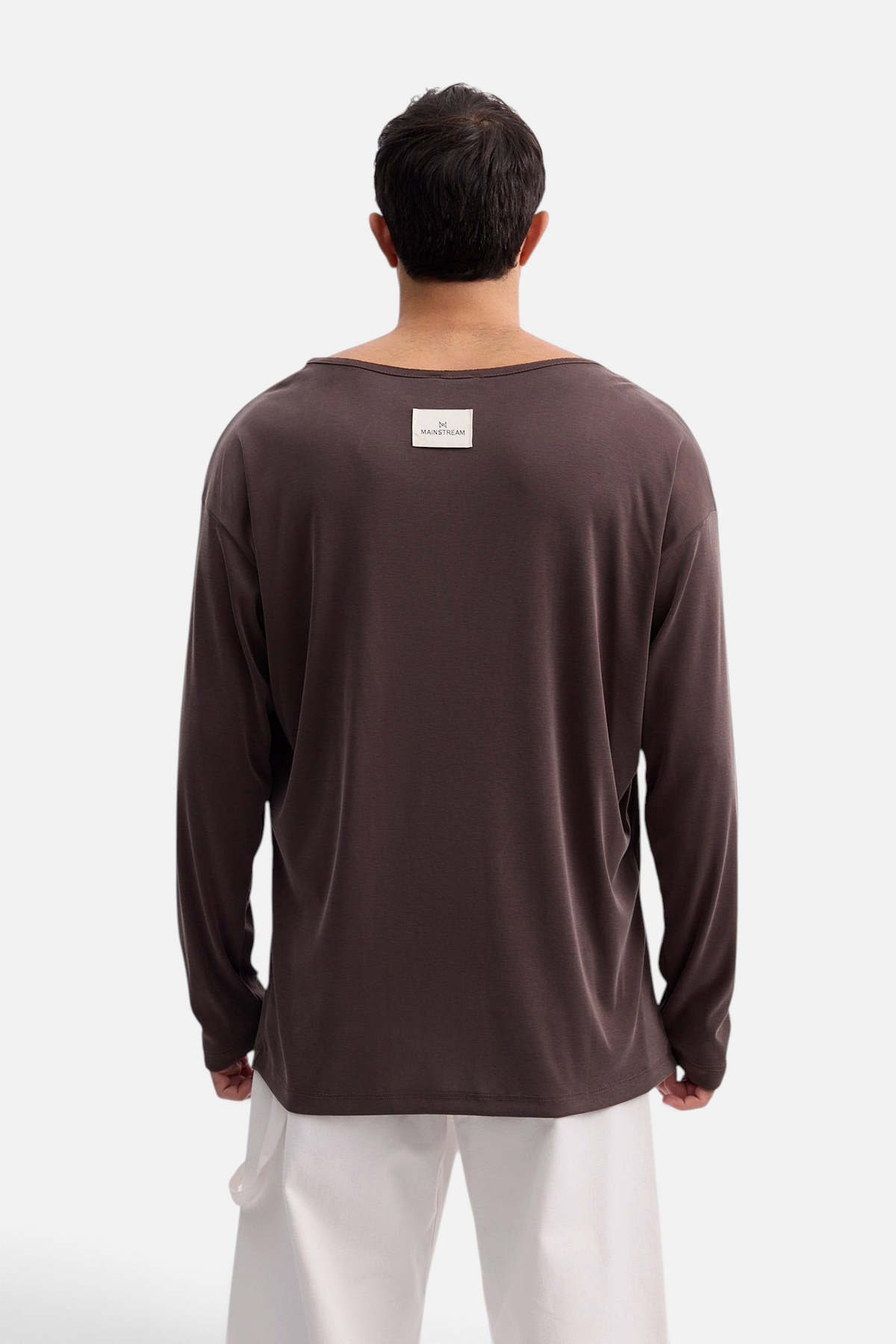 Back view of a man wearing a Mainstreamonline Niki long sleeve oversized brown t-shirt with a brand label