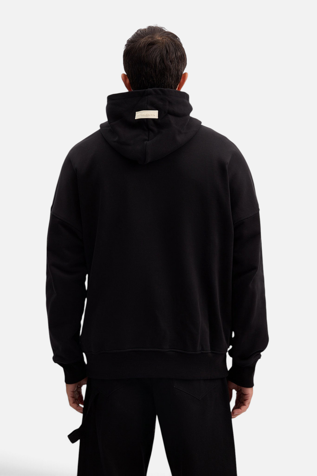 Mainstreamonline black oversized hoodie with a relaxed fit and branded label on the hood, back view