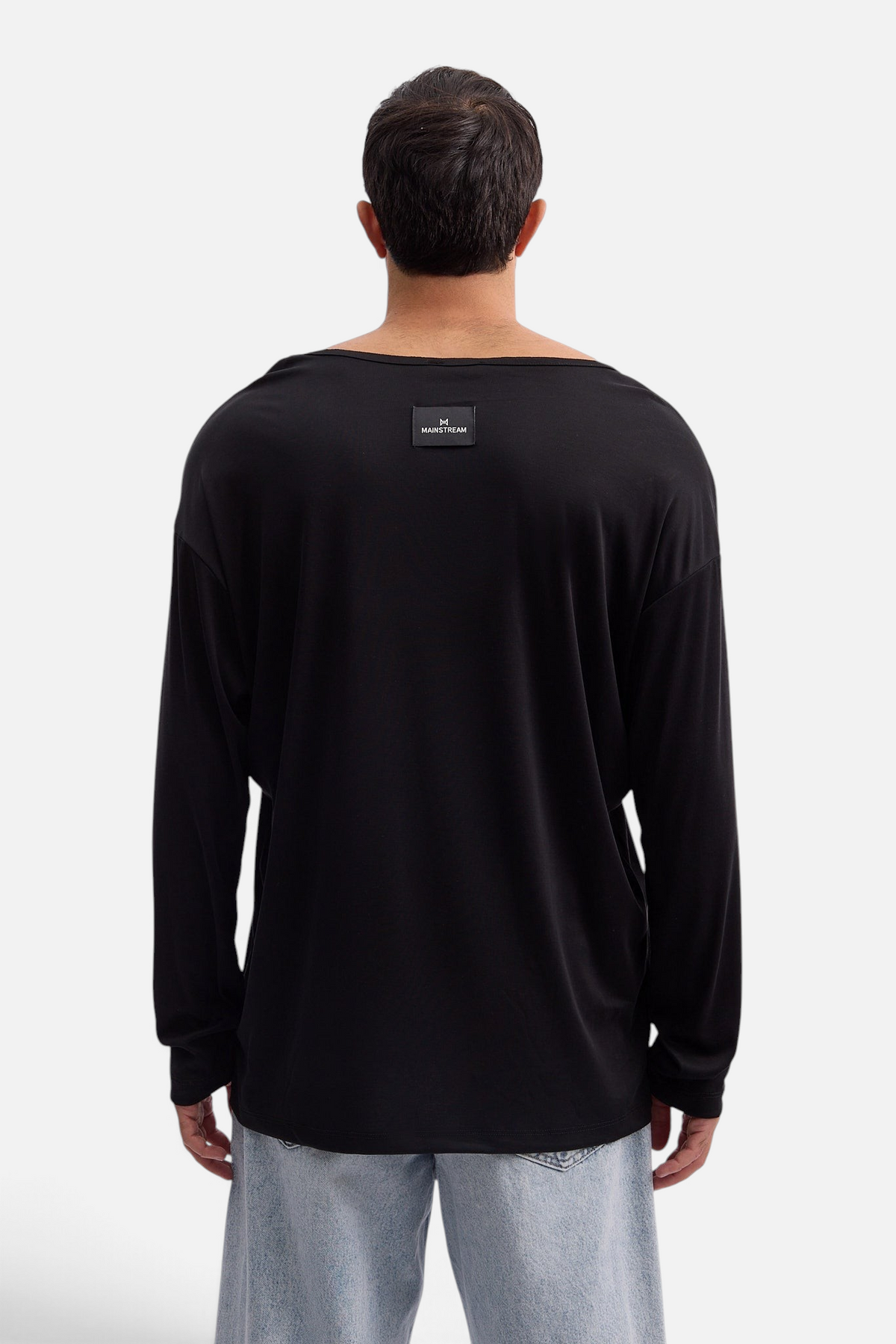 Mainstreamonline Niki long sleeve black oversized t-shirt with a back neck logo patch worn by a man