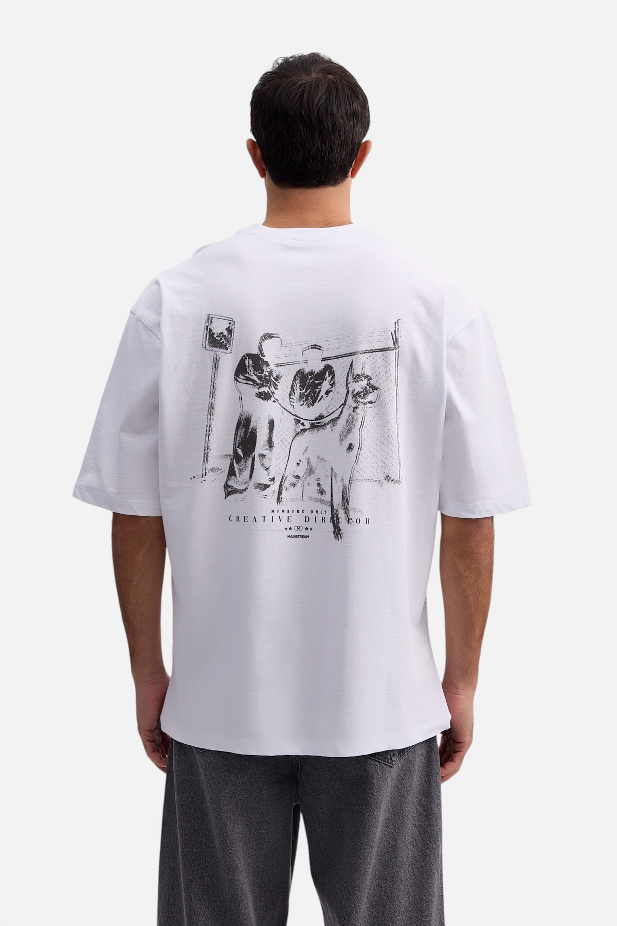 Mainstreamonline white oversized t-shirt with black graphic print on the back worn by a man