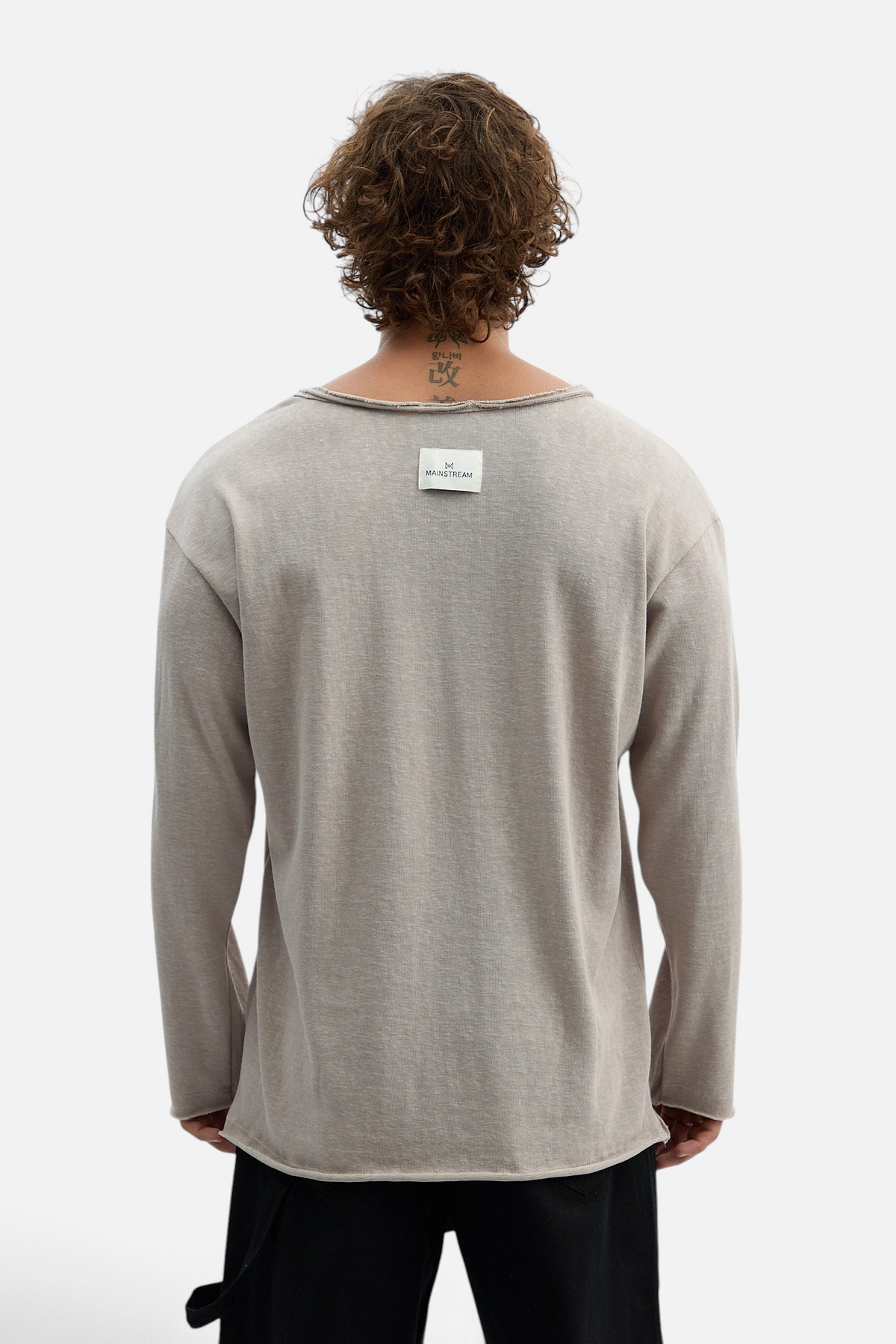 Mainstreamonline beige long sleeve oversized Bali t-shirt with raw hem and back label detail on a male model