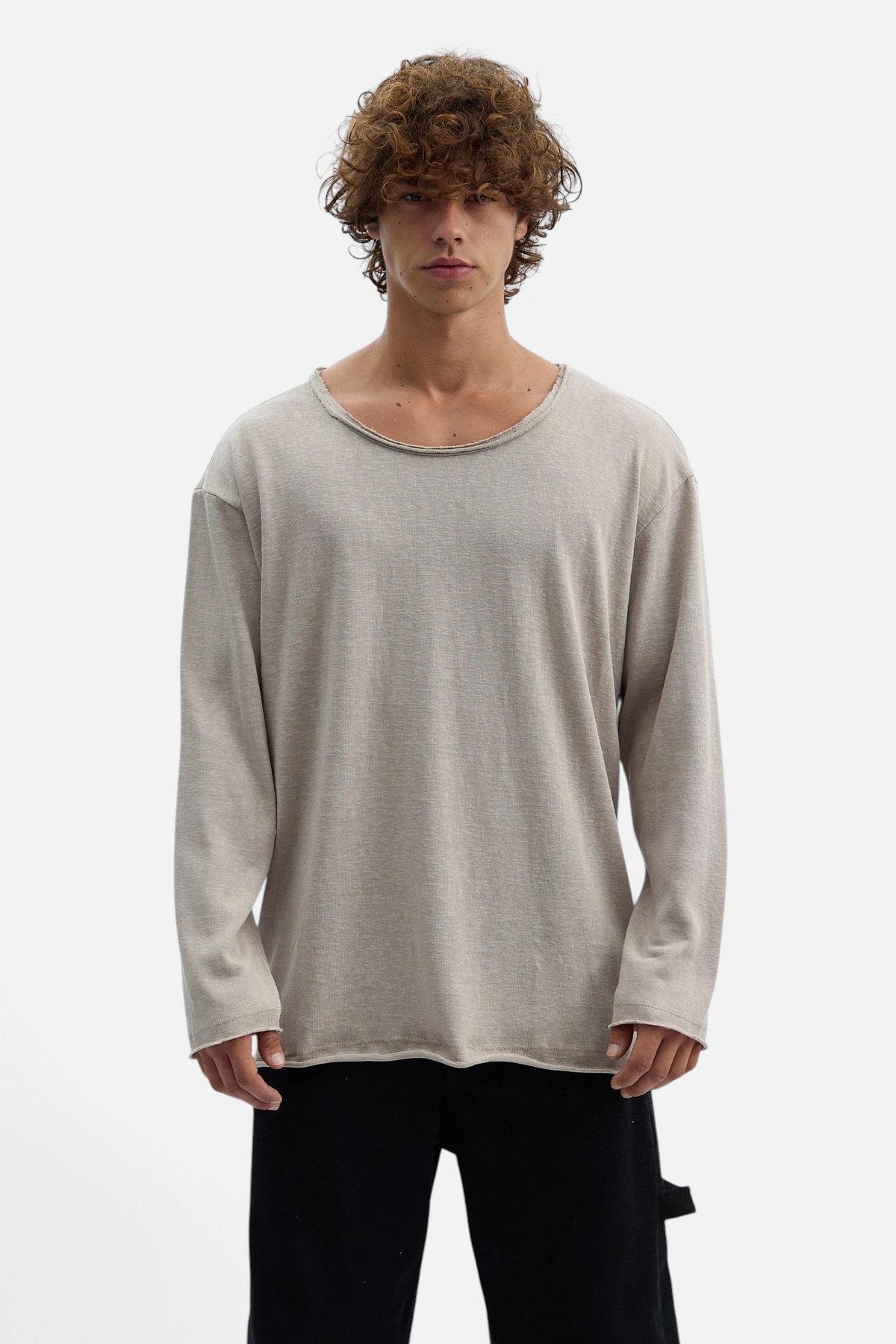 Mainstreamonline beige long sleeve oversized t-shirt with a raw edge neckline worn by a curly-haired male model