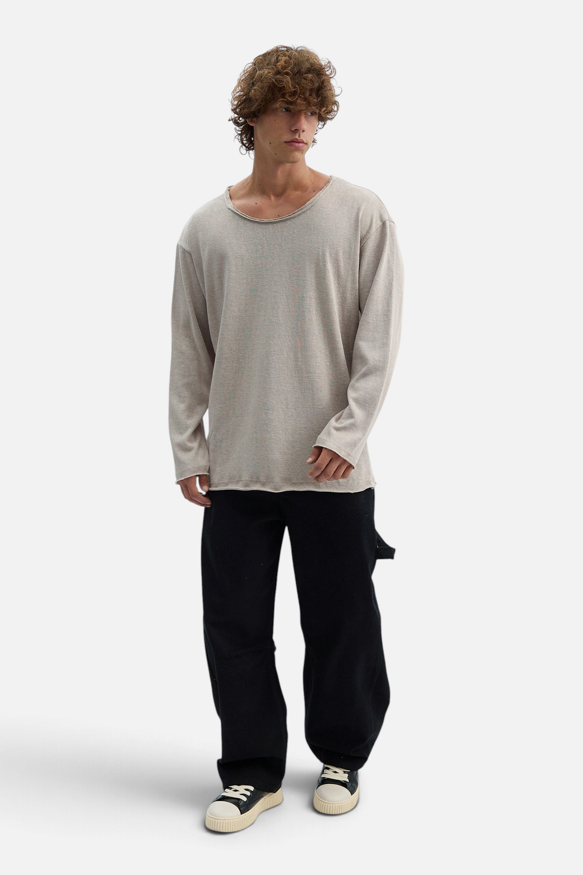 Mainstreamonline beige long sleeve oversized Bali t-shirt with a raw neckline worn by a curly-haired male model