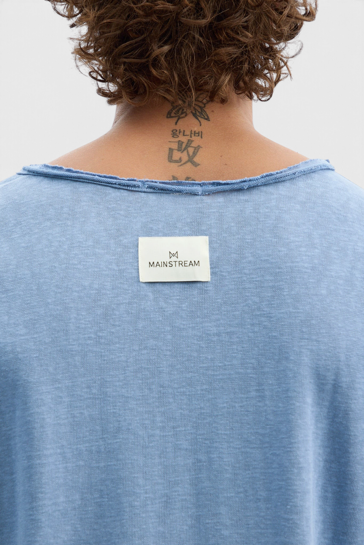 Mainstreamonline blue long sleeve oversized t-shirt with a raw edge neckline and branded label on the back