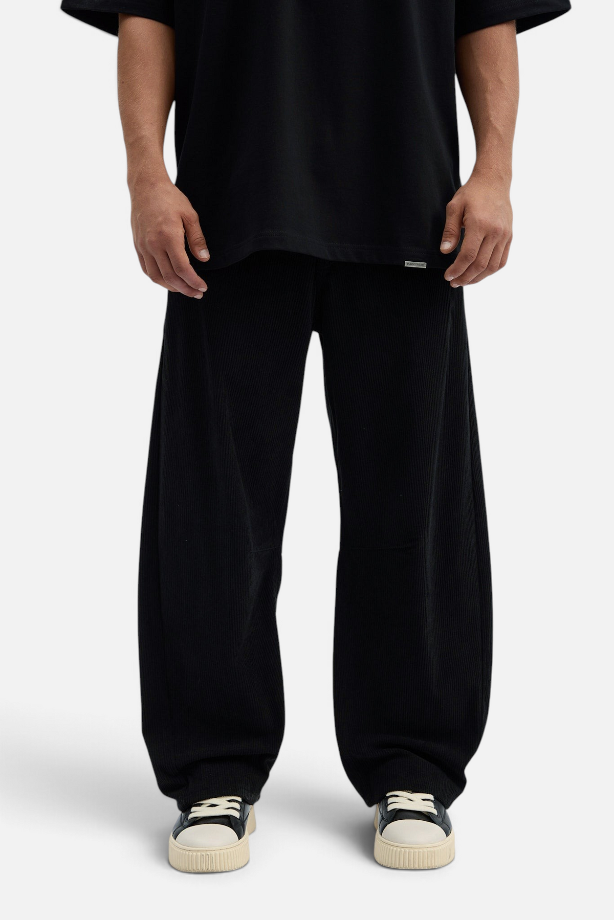 Mainstreamonline black corduroy baggy pants with a loose, wide-leg fit worn by a model in a studio setting.