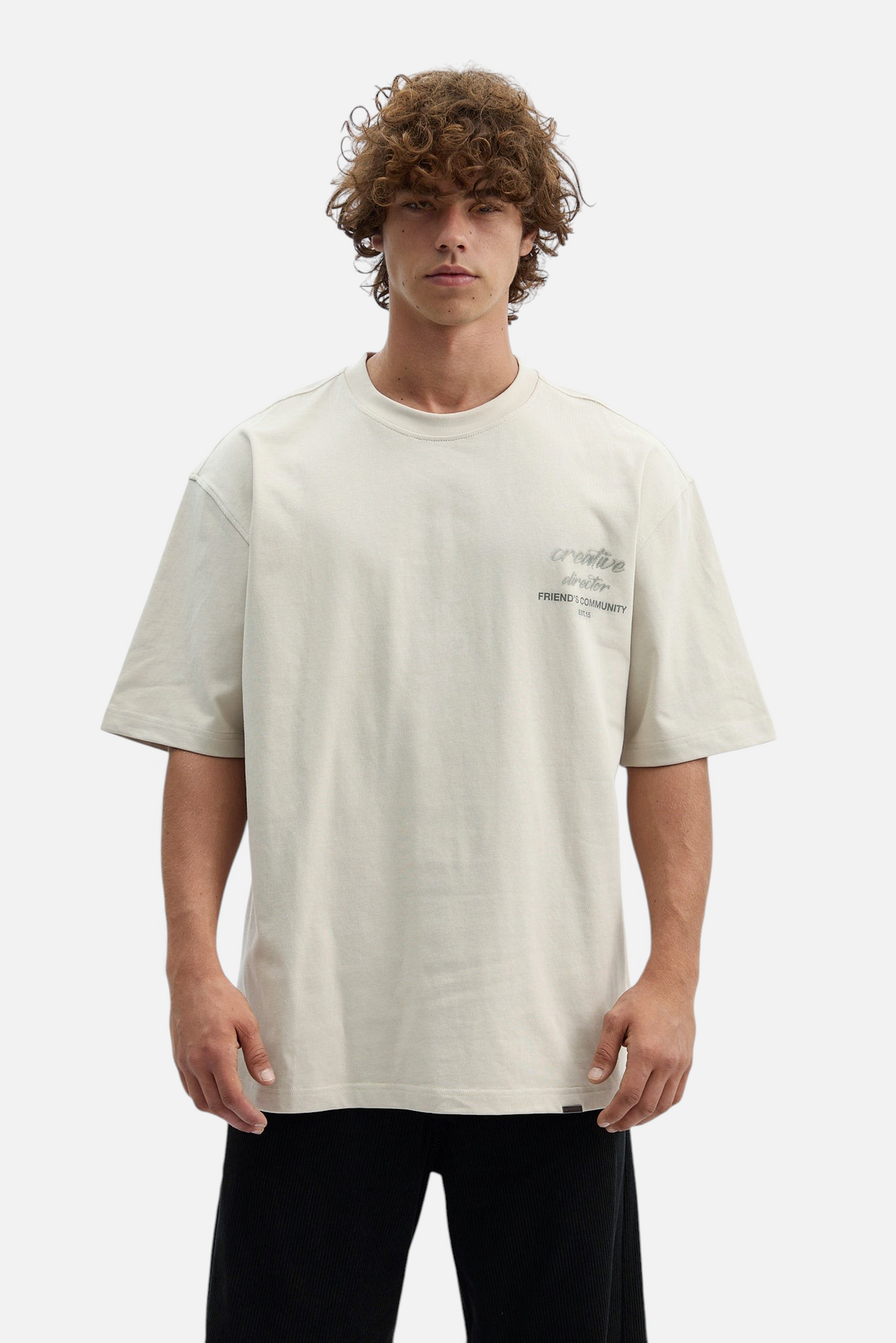 Mainstreamonline oversized beige t-shirt with creative director graphic print on chest worn by a male model