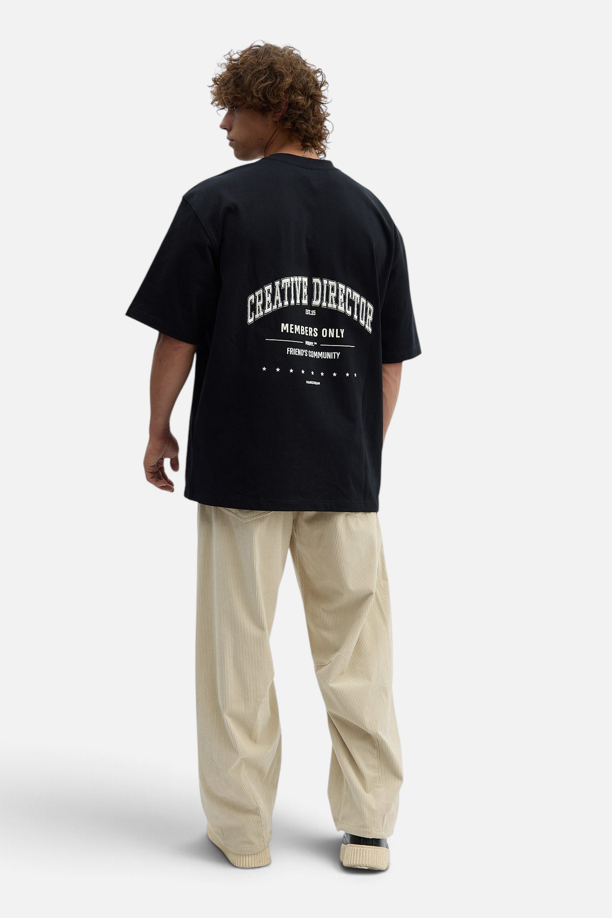 Mainstreamonline beige corduroy baggy pants paired with a black graphic t-shirt on a male model, back view