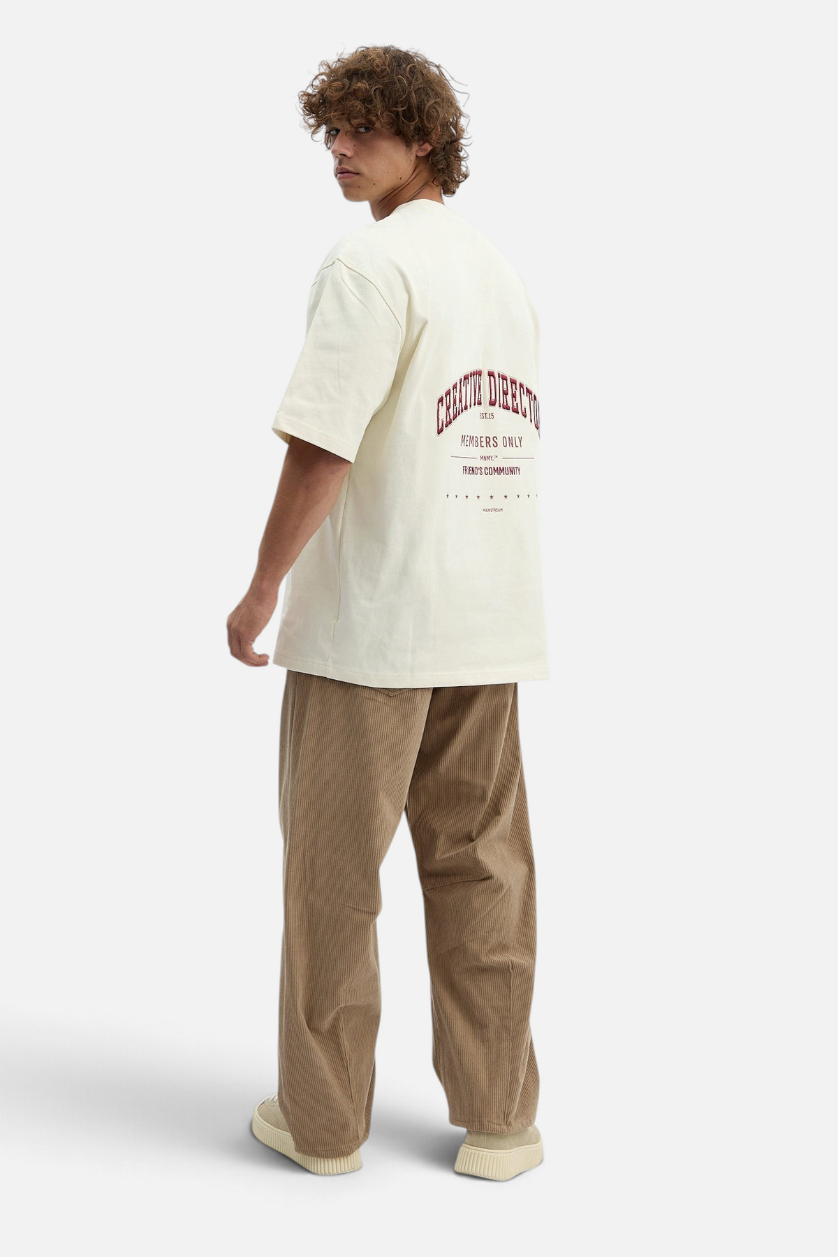 Mainstreamonline baggy brown corduroy pants worn by a man with a graphic t-shirt, back view