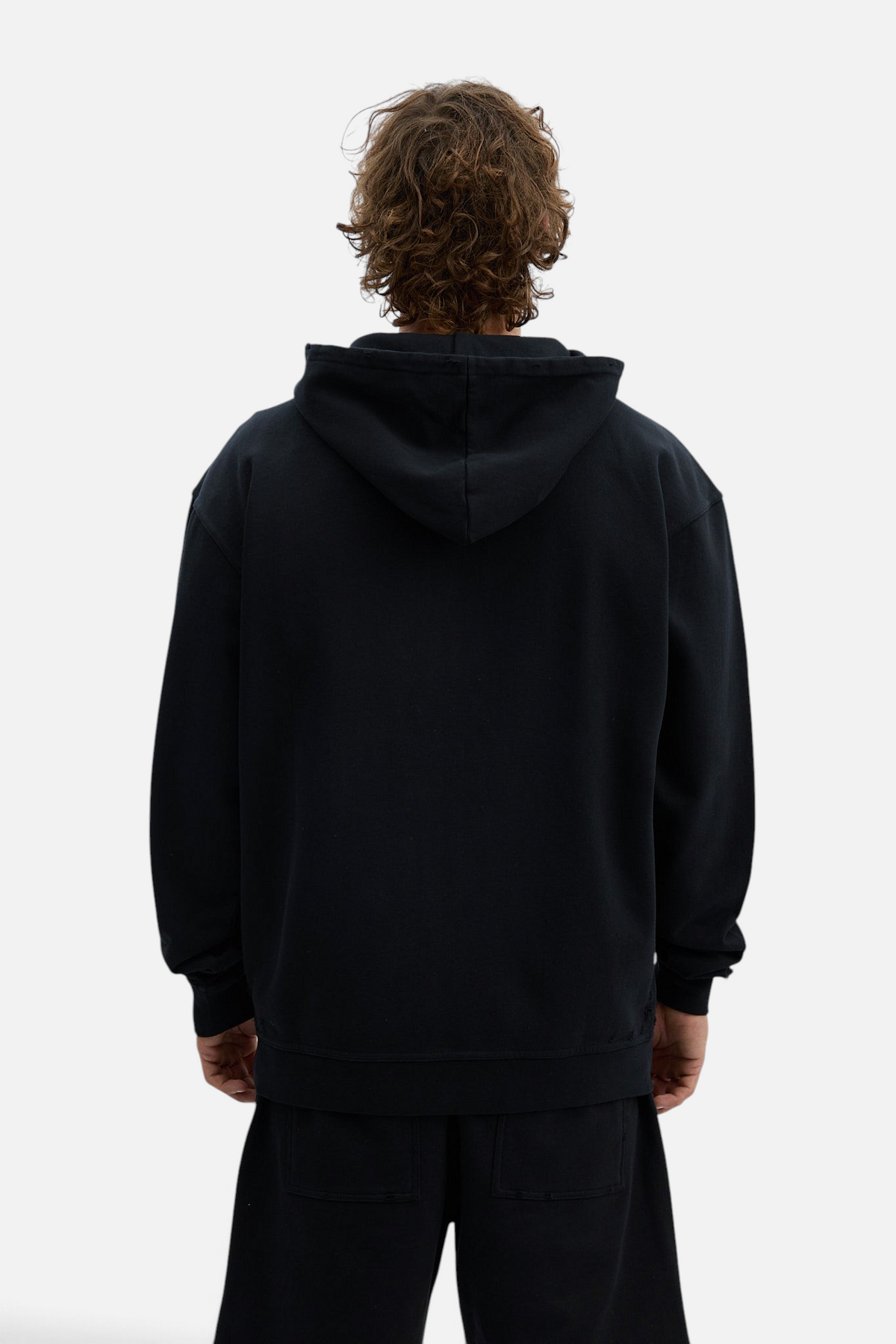 Mainstreamonline Rifts oversized black zip hoodie worn by a man, back view showing loose fit and hood