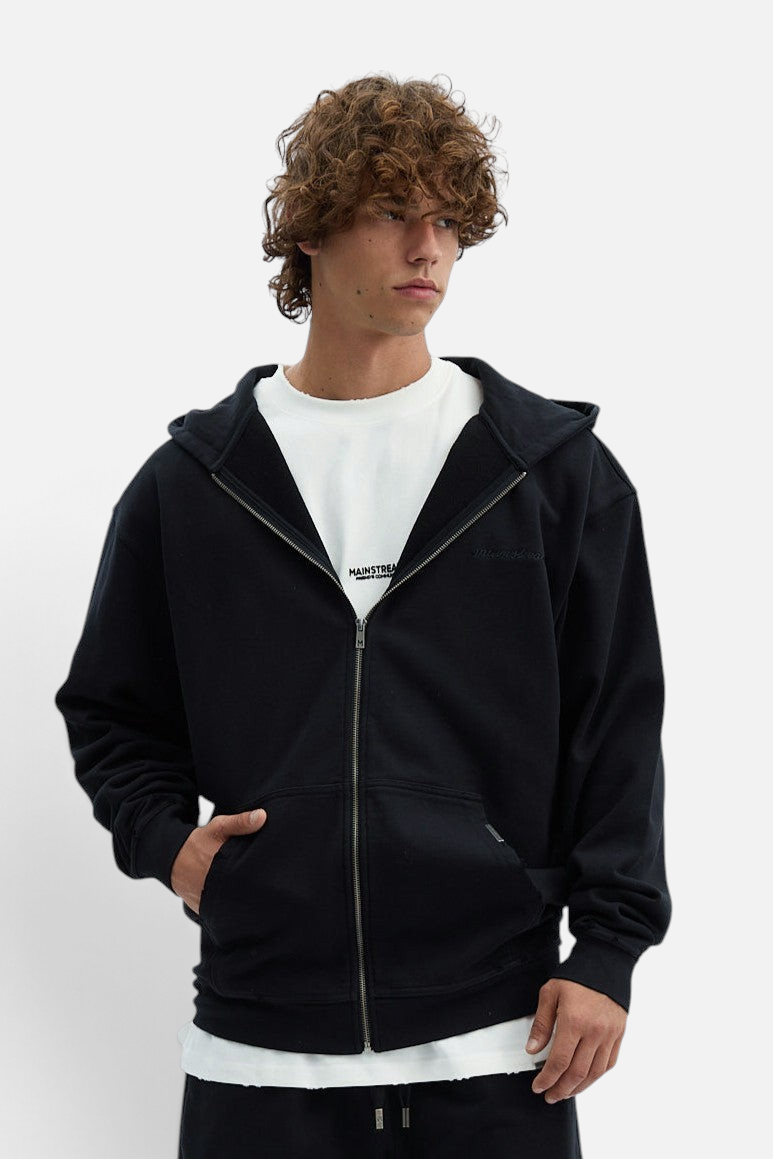 Mainstreamonline Rifts oversized black zip-up hoodie worn by a model with curly hair
