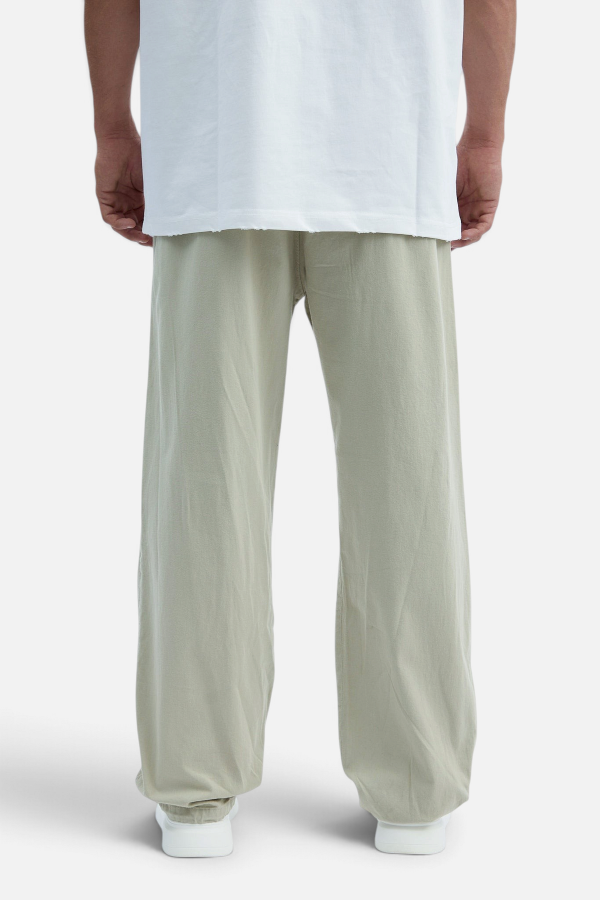 Mainstreamonline baggy jeans in light sage green with a loose, relaxed fit worn with a white t-shirt, back view