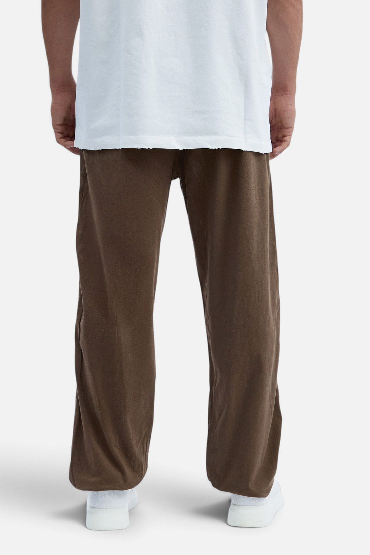Mainstreamonline baggy brown jeans with a loose, relaxed fit worn with a white t-shirt and white sneakers
