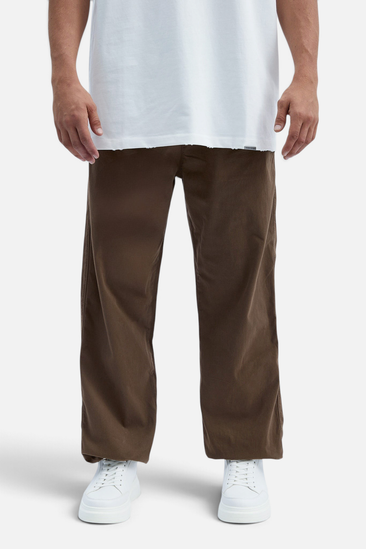 Mainstreamonline brown baggy jeans with a loose, relaxed fit worn by a model with a white t-shirt and white sneakers
