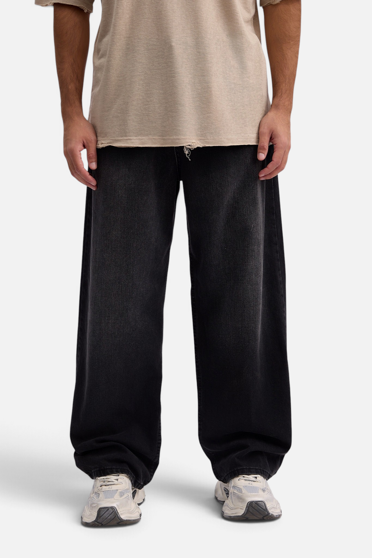 Mainstreamonline baggy skater jeans in washed black denim with a loose, wide-leg fit worn with a beige t-shirt